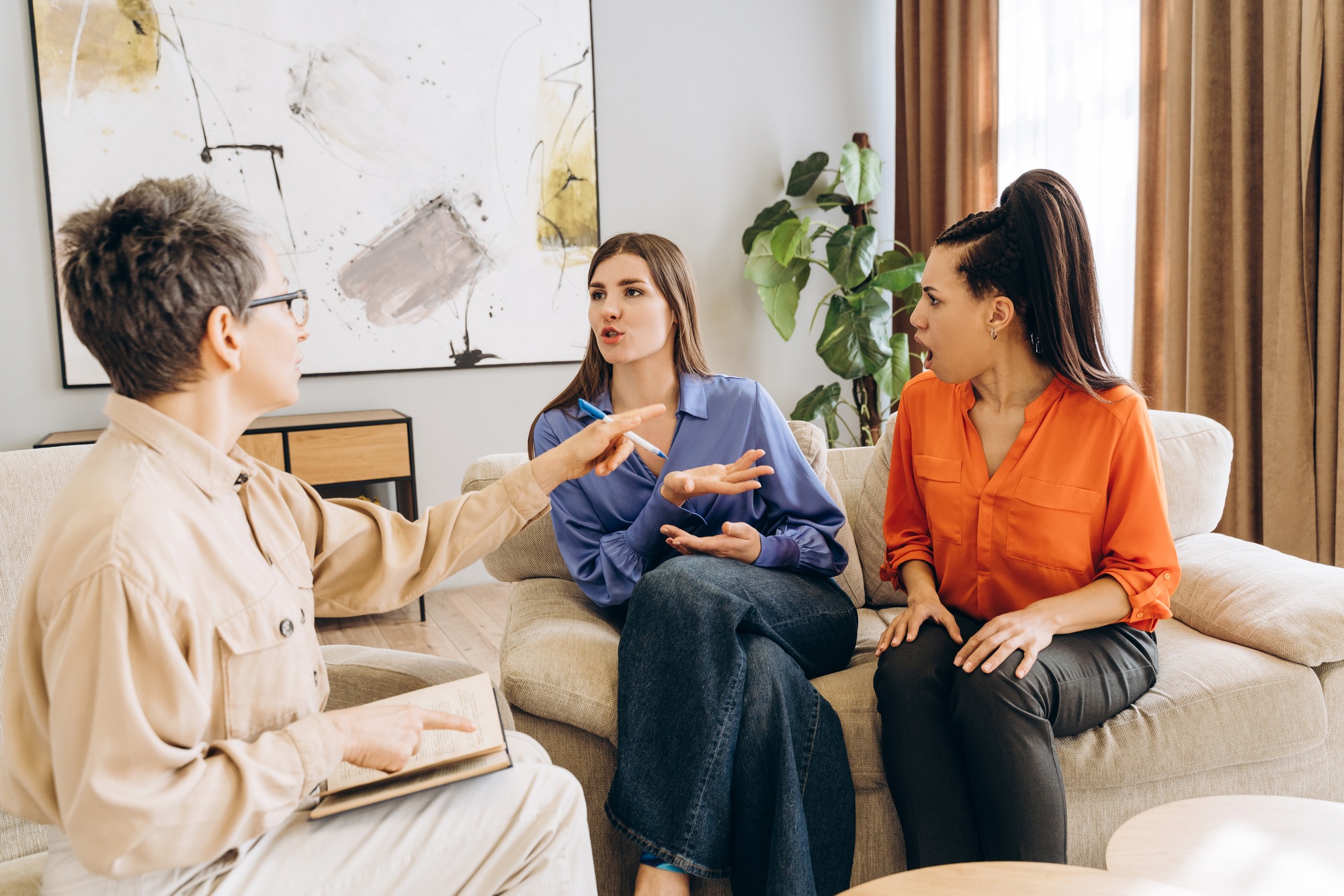 Psychologist mediating family conflict between mother and daughter during therapy session